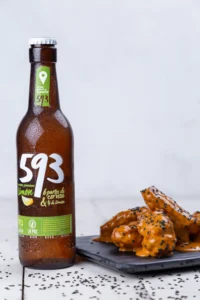 Cerveza junto a plato con alitas en restaurante.