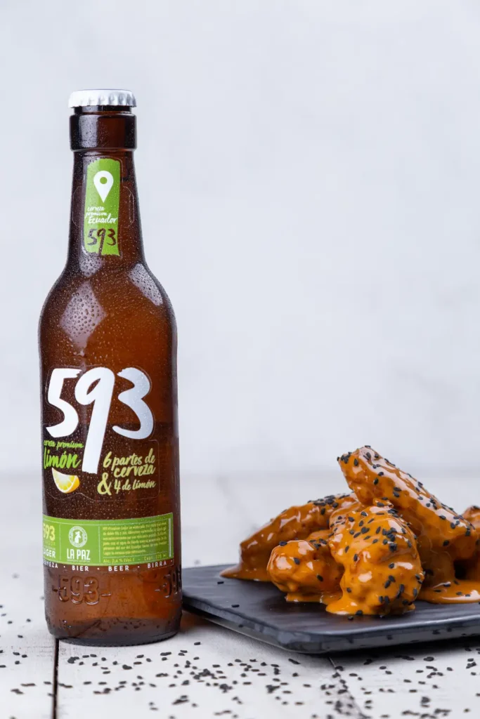 Cerveza junto a plato con alitas en restaurante.