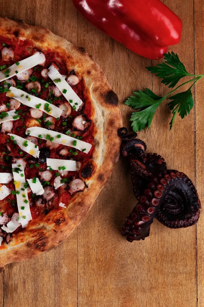 Pizza artesanal con decoración elegante fotografiado profesionalmente.