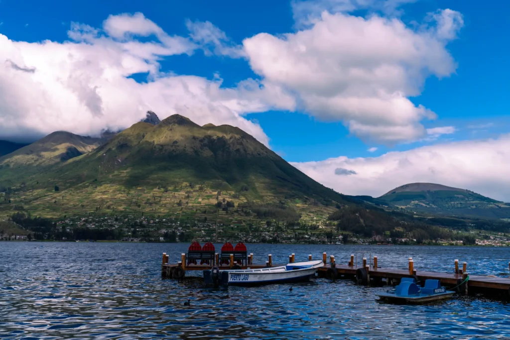 Fotografía aérea con dron de un muelle sobre un lago con montañas al fondo en Ecuador