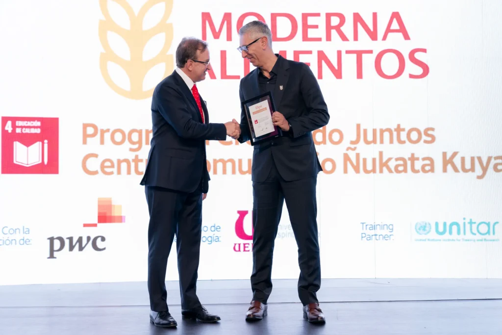 CEO recibiendo un premio en escenario durante una ceremonia corporativa, en presencia de audiencia y con iluminación profesional de evento.