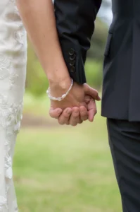 "Primer plano de las manos de los novios entrelazadas mientras caminan durante su boda."